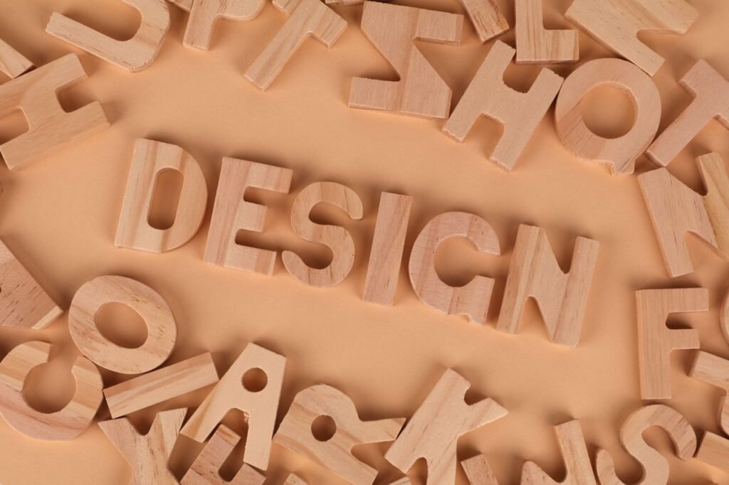Wooden letters arranged to form the word 'design' on a brown background, top view.