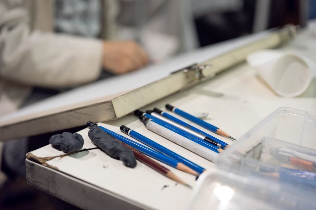 Close-up of art supplies and sketching pencils on a desk, suggesting a creative workspace.